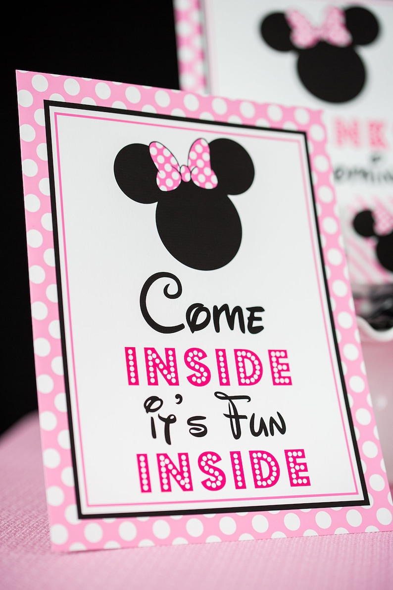 May include: Pink and white polka dot sign with a black and white image of Minnie Mouse. The sign says "Come Inside It's Fun Inside".