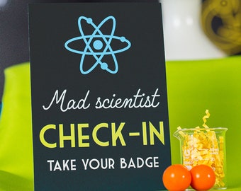 May include: Black sign with a blue atom symbol, the text "Mad scientist check-in" in yellow, and the text "Take your badge" in white.