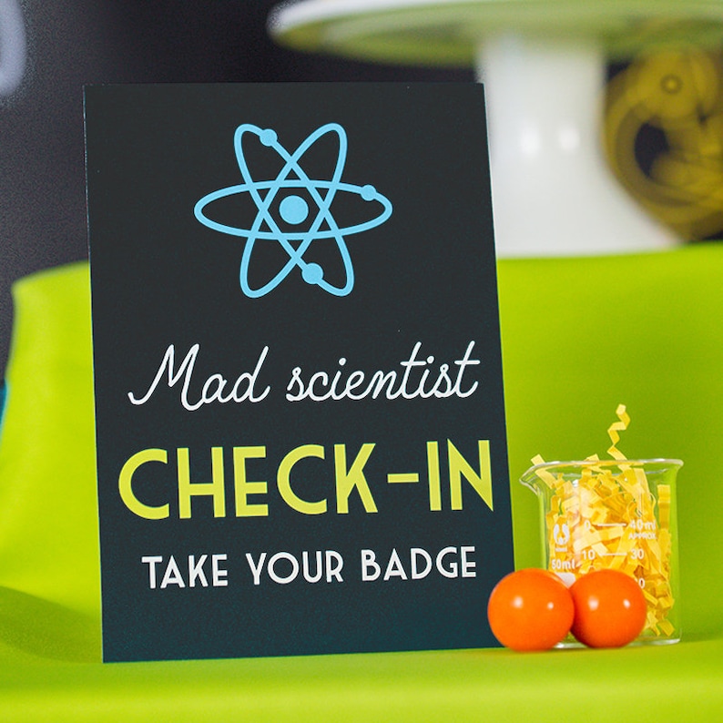 May include: Black sign with a blue atom symbol, the text "Mad scientist check-in" in yellow, and the text "Take your badge" in white.
