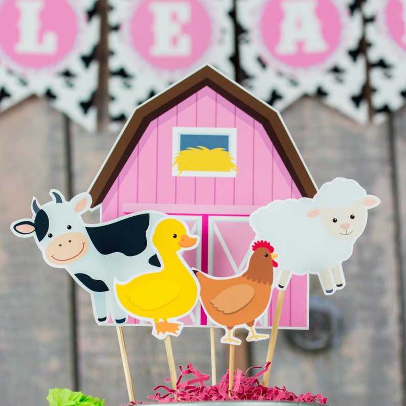 Puede incluir: Un granero rosa con un pajar de heno amarillo en la ventana, una vaca blanca y negra, un pato amarillo, una gallina marr&oacute;n y una oveja blanca. Los animales de granja est&aacute;n en palos, perfectos para una fiesta con tem&aacute;tica de granja.