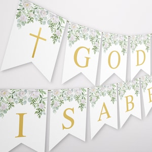 Puede incluir: Bandera blanca con hojas verdes y flores blancas. La bandera tiene letras doradas que deletrean "GOD IS ABE". Hay una cruz dorada en la primera bandera.