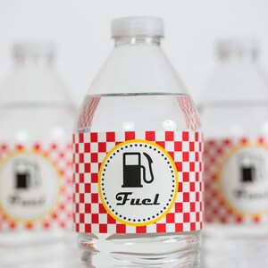 May include: Three clear plastic water bottles with red and white checkered labels. The labels have a yellow circle with a black gas pump icon and the word "Fuel" in black text.