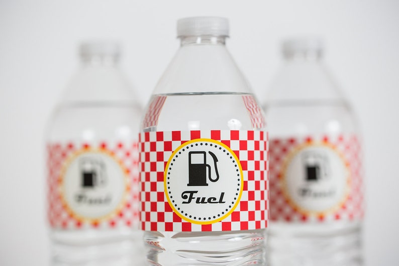 May include: Three clear plastic water bottles with red and white checkered labels. The labels have a yellow circle with a black gas pump icon and the word "Fuel" in black text.