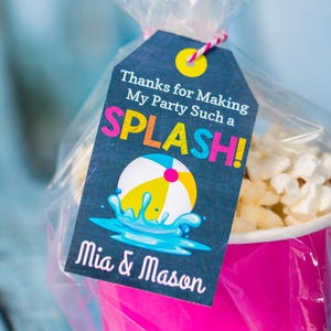 May include: A black and white favour tag with a colourful beach ball and the text "Thanks for Making My Party Such a SPLASH! Mia & Mason".