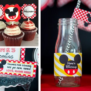 May include: Cupcakes with red and white frosting, topped with Mickey Mouse-themed decorations. A glass bottle with a yellow and white striped label and a Mickey Mouse design. Party favors with a Mickey Mouse theme.