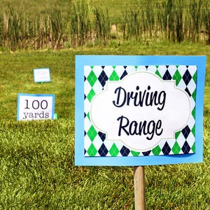 May include: A blue sign with a green and black diamond pattern reads "Driving Range". There are two smaller signs in the background that read "100 yards" and "300 yards".