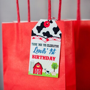 May include: Red and white favour bag with a tag that says "Thank 'Moo' for celebrating Lenis' 1st Birthday". The tag has a cow print, red and white checked pattern, and a farm scene with a barn, silo, cow, and pig.