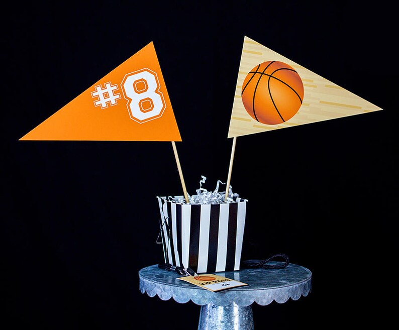 May include: Two orange and white pennants with the number 8 and a basketball design, a black and white striped container, and a small silver cake stand with a tag that says "MVP Party".