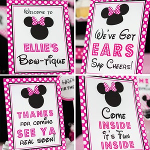 Puede incluir: Cuatro carteles de lunares rosas y blancos con una silueta negra de Minnie Mouse. Los carteles dicen "Bienvenido a Ellie's Bow-tique", "Tenemos Orejas &iexcl;Salud!", "Gracias por venir &iexcl;Nos vemos pronto!" y "Entra Es divertido dentro".
