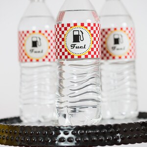 May include: Three clear plastic water bottles with red and white checkered labels that say "Fuel" with a gas pump icon. The bottles are on a black and red tiered stand.