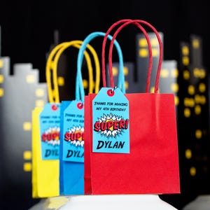 May include: Four red, blue, and yellow gift bags with tags that say "Thanks for making my 4th birthday super! Dylan".