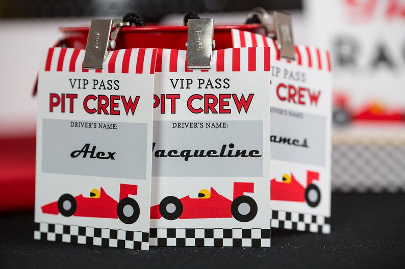 May include: Three red, white and black VIP pass cards with the text "VIP Pass Pit Crew" and a red race car graphic. The cards have a blank space for a driver's name. The names "Alex", "Jacqueline", and "James" are written on the cards.