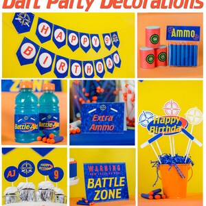 May include: Dart party decorations with a blue and orange color scheme. The decorations include a banner that says "Happy 9th Birthday", a sign that says "Extra Ammo", a sign that says "Warning Battle Zone", and a sign that says "Happy Birthday". There are also blue and orange dart guns and a bucket filled with blue tissue paper.