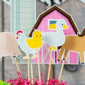 Puede incluir: Un conjunto de adornos para cupcakes con tem&aacute;tica de animales de granja. Los adornos incluyen un cerdo rosa, una gallina blanca, un pollito amarillo, un pato blanco, un caballo marr&oacute;n y un granero rosa.