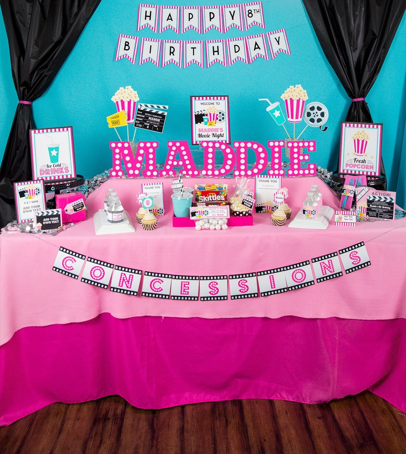 May include: A pink and black movie-themed party table with a banner that says "CONCESSIONS" and a sign that says "Maddie's Movie Night". There are various decorations, including popcorn, film reels, and a sign that says "Happy 8th Birthday".