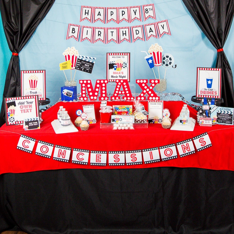May include: A movie-themed birthday party setup with a red and black color scheme. The table is decorated with popcorn, film reels, and signs that say "Happy 8th Birthday", "Concessions", and "Max's Movie Night".