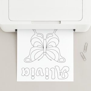 May include: A white sheet of paper emerging from a white printer featuring a black line art drawing of a butterfly and the name Alivia written in a stylised bubble font. Two silver metal paper clips are positioned to the right of the paper.