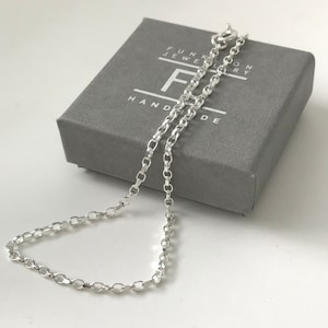 May include: A silver chain necklace in a grey box with the text "FUNKY JEWELRY HANDMADE".