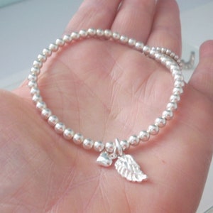 May include: A silver beaded bracelet with a small silver heart and angel wing charm.