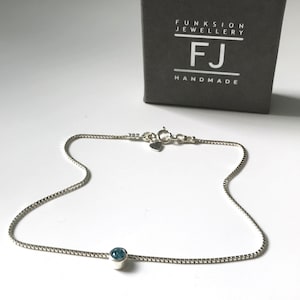 May include: A silver chain anklet with a small blue gemstone. The anklet is handmade and comes in a box that says "Funksion Jewellery FJ Handmade".