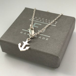 May include: A silver anchor charm necklace in a grey box with the text "Junksilver Jewellery Handmade".