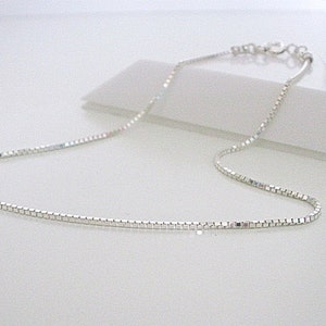 May include: A silver chain necklace with a box chain design.