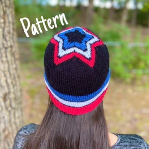 Pode incluir: Um chapéu de malha preto com um design de estrela vermelho, branco e azul. O chapéu tem uma aba e é dobrado para baixo na parte superior. O chapéu está sendo usado por uma pessoa com cabelo castanho longo.