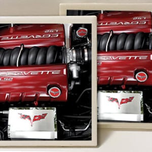 May include: Two red Corvette engine block coasters with the text "Corvette" and "LS2" on the engine block. The coasters have a black and white image of a Corvette logo on the bottom.