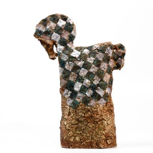 Pode incluir: Uma escultura de cerâmica de um cavalo com uma base castanha texturizada e rachada. A parte superior do corpo apresenta um padrão de xadrez distinto em tons alternados de verde escuro, branco e prata metálica, com pescoço e cabeça curvados.