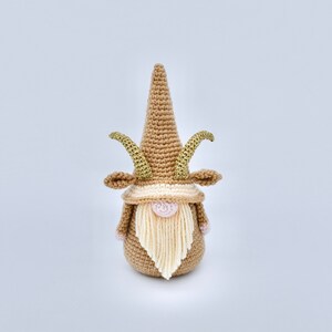 May include: A crocheted gnome with a brown hat and beard, gold horns, and a pink nose.