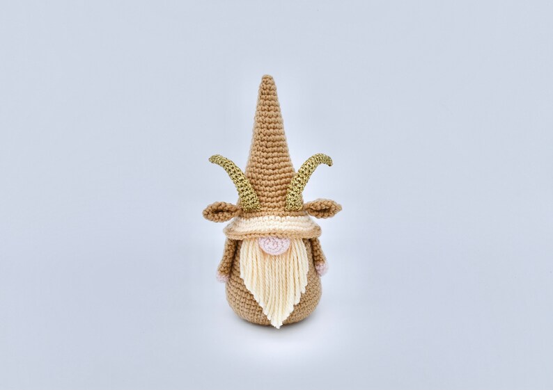 May include: A crocheted gnome with a brown hat and beard, gold horns, and a pink nose.