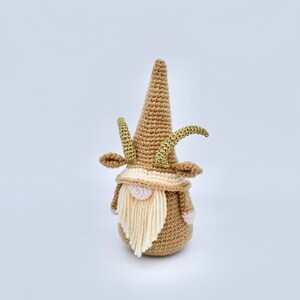 May include: A crocheted gnome with a brown hat and beard, gold horns, and pink cheeks.