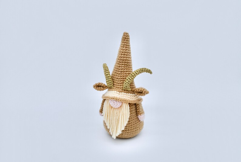 May include: A crocheted gnome with a brown hat and beard, gold horns, and pink cheeks.
