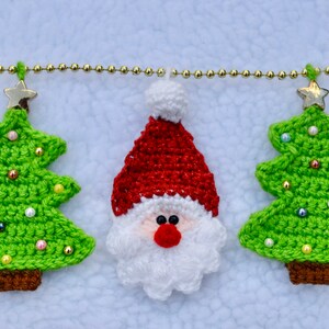May include: A crocheted Christmas garland with green trees, a Santa Claus, and gold beads.