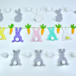 Könnte beinhalten: Eine Girlande aus gehäkelten Hasen mit weißen Pompons dazwischen. Die Hasen sind in verschiedenen Farben, darunter rosa, lila, gelb, blau und grau.