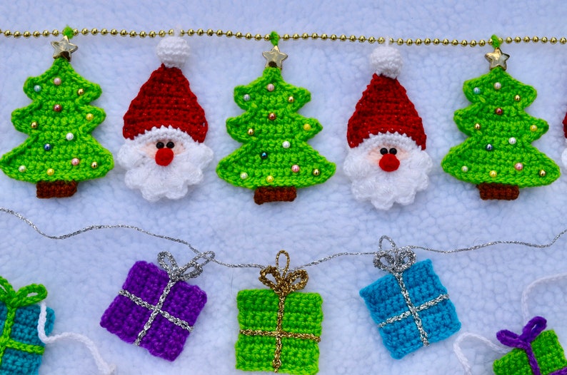 May include: A crocheted Christmas garland with green and red Christmas trees, Santa Claus figures, and green and purple gift boxes.