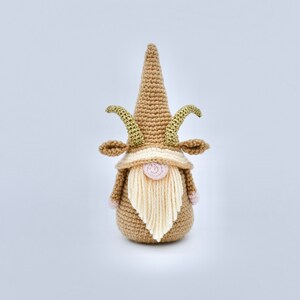 May include: A crocheted gnome with a brown hat and beard, gold horns, and pink cheeks.