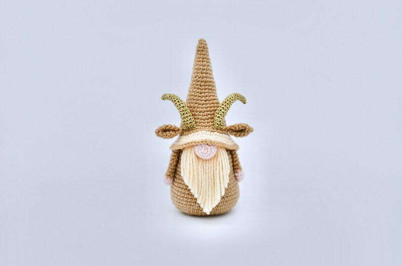 May include: A crocheted gnome with a brown hat and beard, gold horns, and pink cheeks.