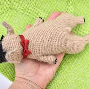 May include: A crocheted tan dog toy with black eyes and a red bow tie.