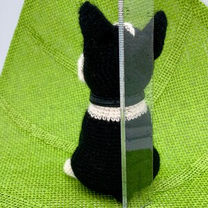 Pu&ograve; includere: Un giocattolo per cani Boston Terrier in crochet nero e bianco, alto circa 38 cm, seduto su una superficie verde.