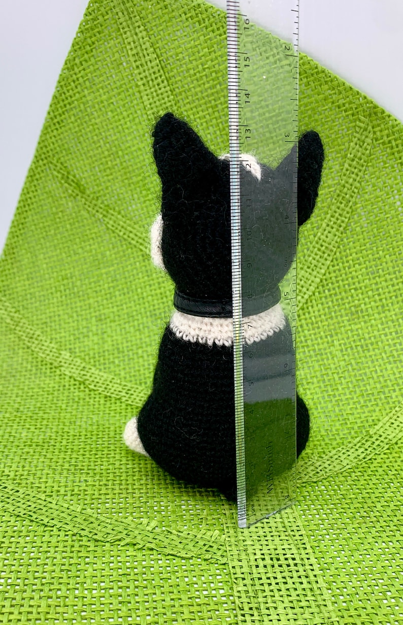 Pu&ograve; includere: Un giocattolo per cani Boston Terrier in crochet nero e bianco, alto circa 38 cm, seduto su una superficie verde.