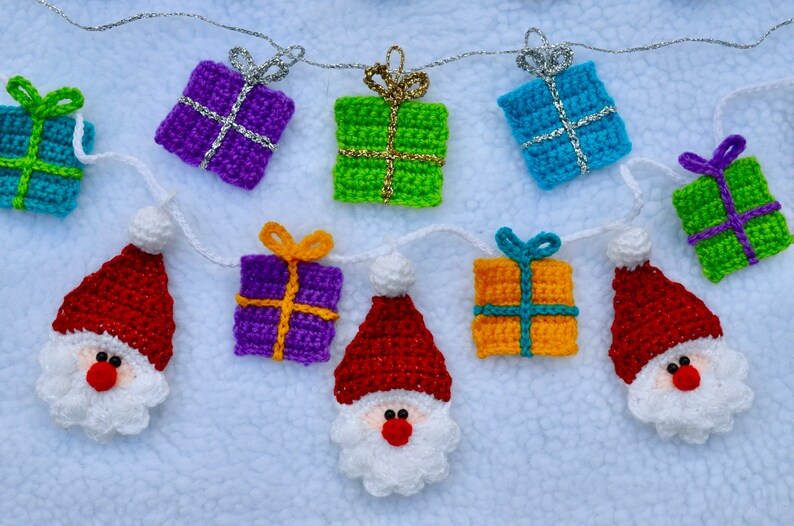 May include: A crocheted Christmas garland with alternating red Santa figures and colorful gift boxes. The garland is strung with silver thread and features a variety of colors, including red, green, blue, purple, and yellow.