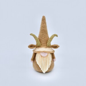 May include: A crocheted gnome with a brown hat and beard, gold horns, and pink cheeks.