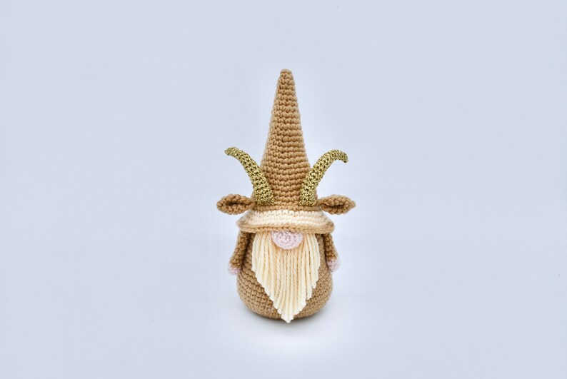 May include: A crocheted gnome with a brown hat and beard, gold horns, and pink cheeks.