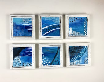 May include: Six small square canvases with white frames, each featuring an abstract blue and white design. The designs include geometric shapes, lines, and dots.