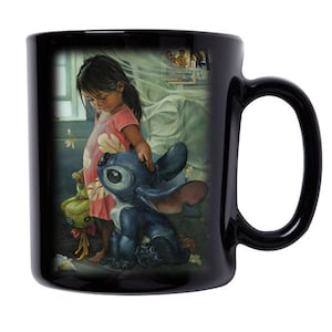 May include: Black ceramic mug with a colorful illustration of a young girl and a blue alien character. The girl is wearing a pink dress with floral patterns and the alien has large eyes and blue fur. The background is a soft, blurry image of a bedroom.
