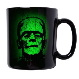 Op de afbeelding: Zwarte koffiemok met een groen-zwarte afbeelding van Frankenstein's monster op de voorkant.