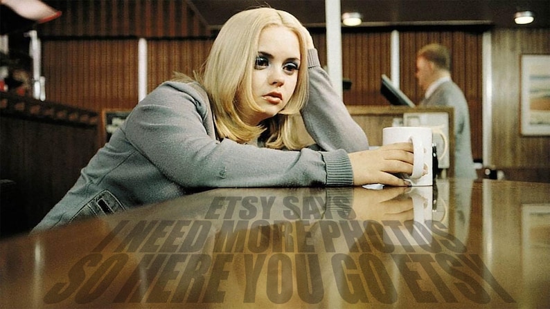 Puede incluir: Una joven con cabello rubio se sienta en una mesa con una taza blanca. La mesa es de madera y tiene una superficie reflectante. El texto "Etsy says I need more photos so here you go Etsy" se refleja en la mesa.