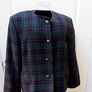 May include: A dark green, red and blue plaid blazer with gold buttons. The blazer has a round neckline and long sleeves.