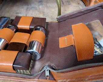 May include: Open brown leather travel case with a zipper closure. The case contains a set of shoe care tools including brushes, polish, and a small mirror.